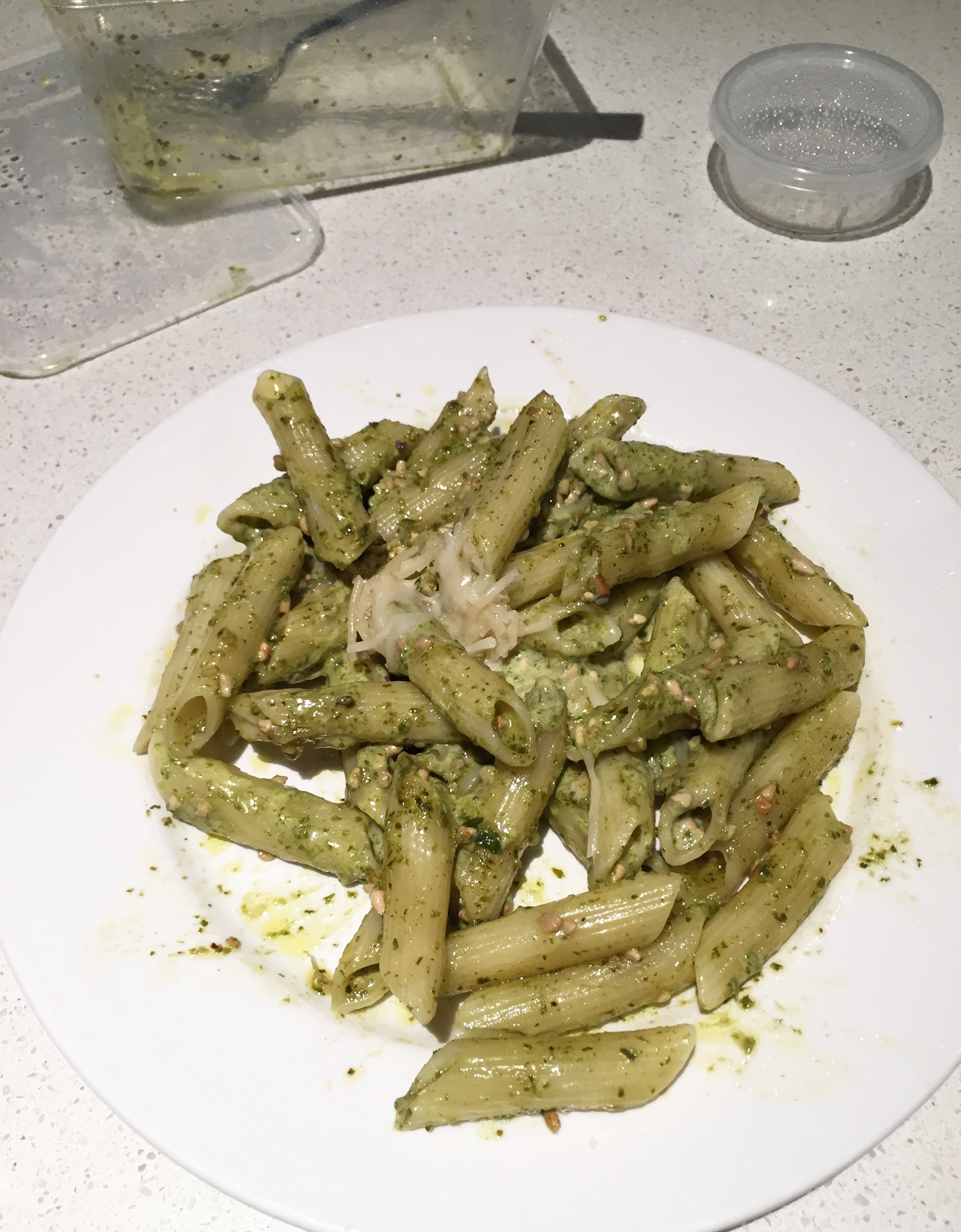 plate of penne pesto pasta and parmesan cheese with take away containers all from Basilico