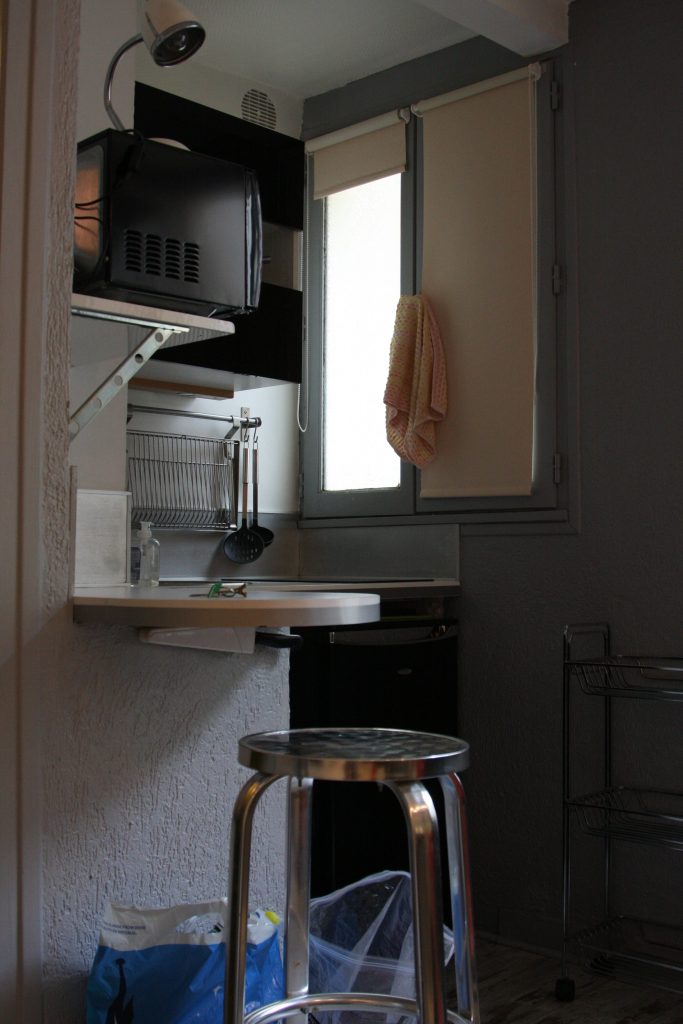 microwave, dishwasher,window, and counter stool in the little kitchenette in the Airbnb rental in Paris