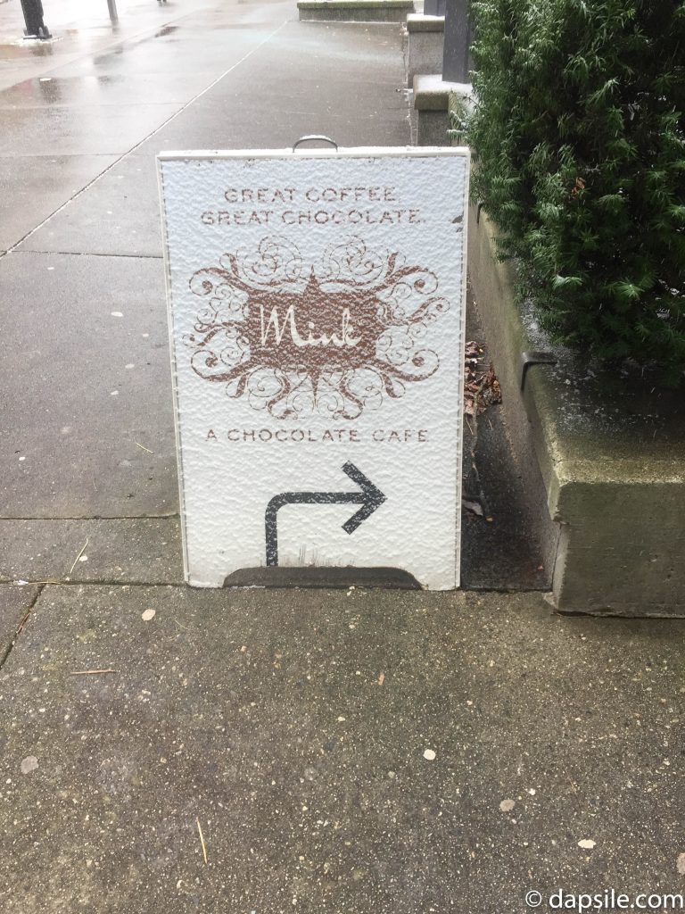 Mink Chocolates Vancouver Folding Street Sign lightly covered with snow