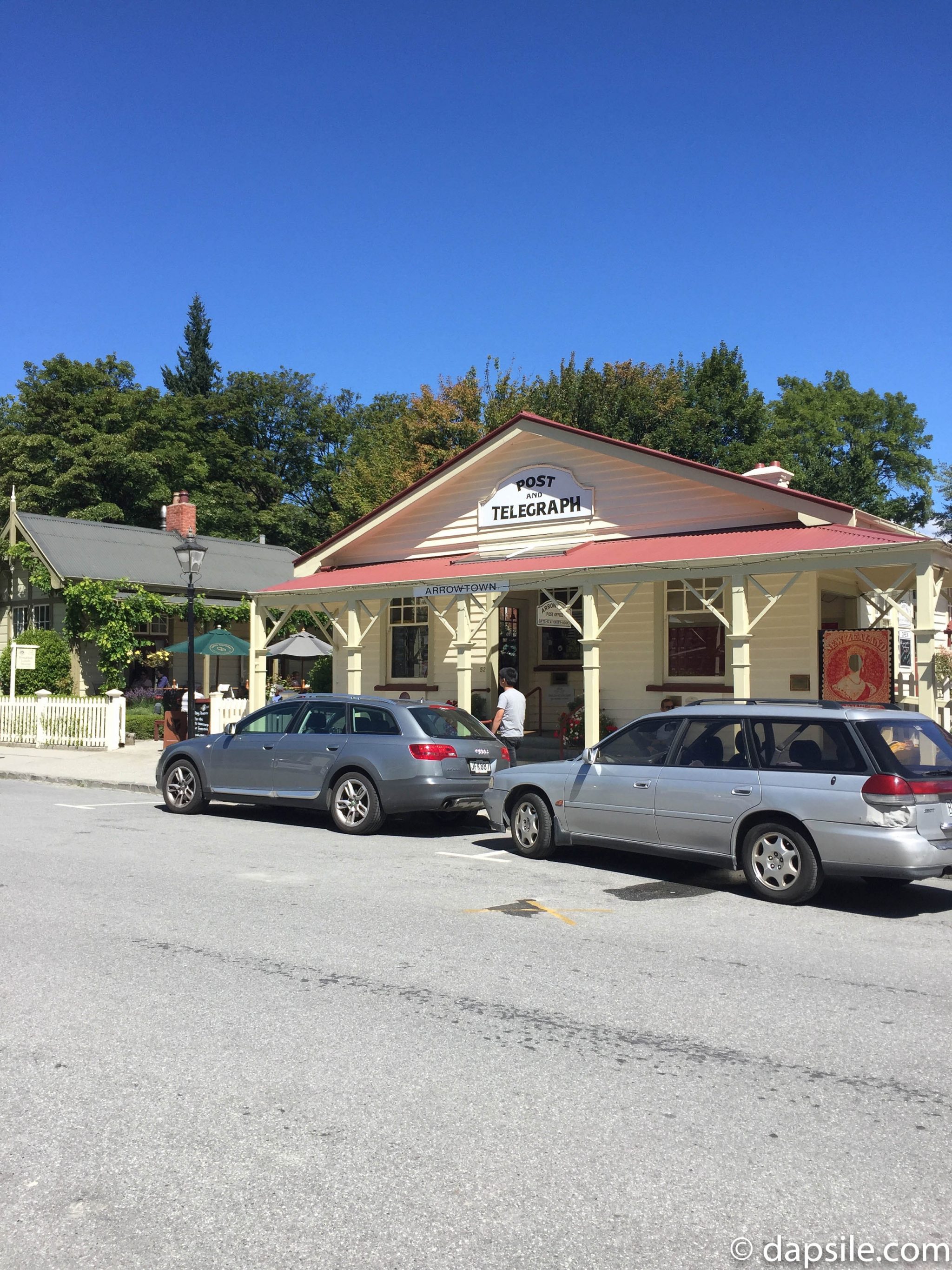 cars parked in front of the Arrowtown post office located in a historical building