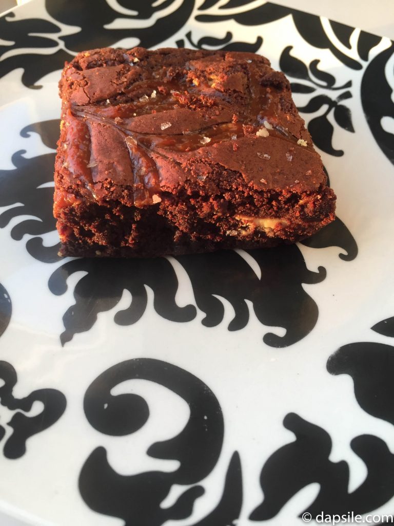 Tartine Salted Caramel White Chocolate Brownie from the side on a black and white plate