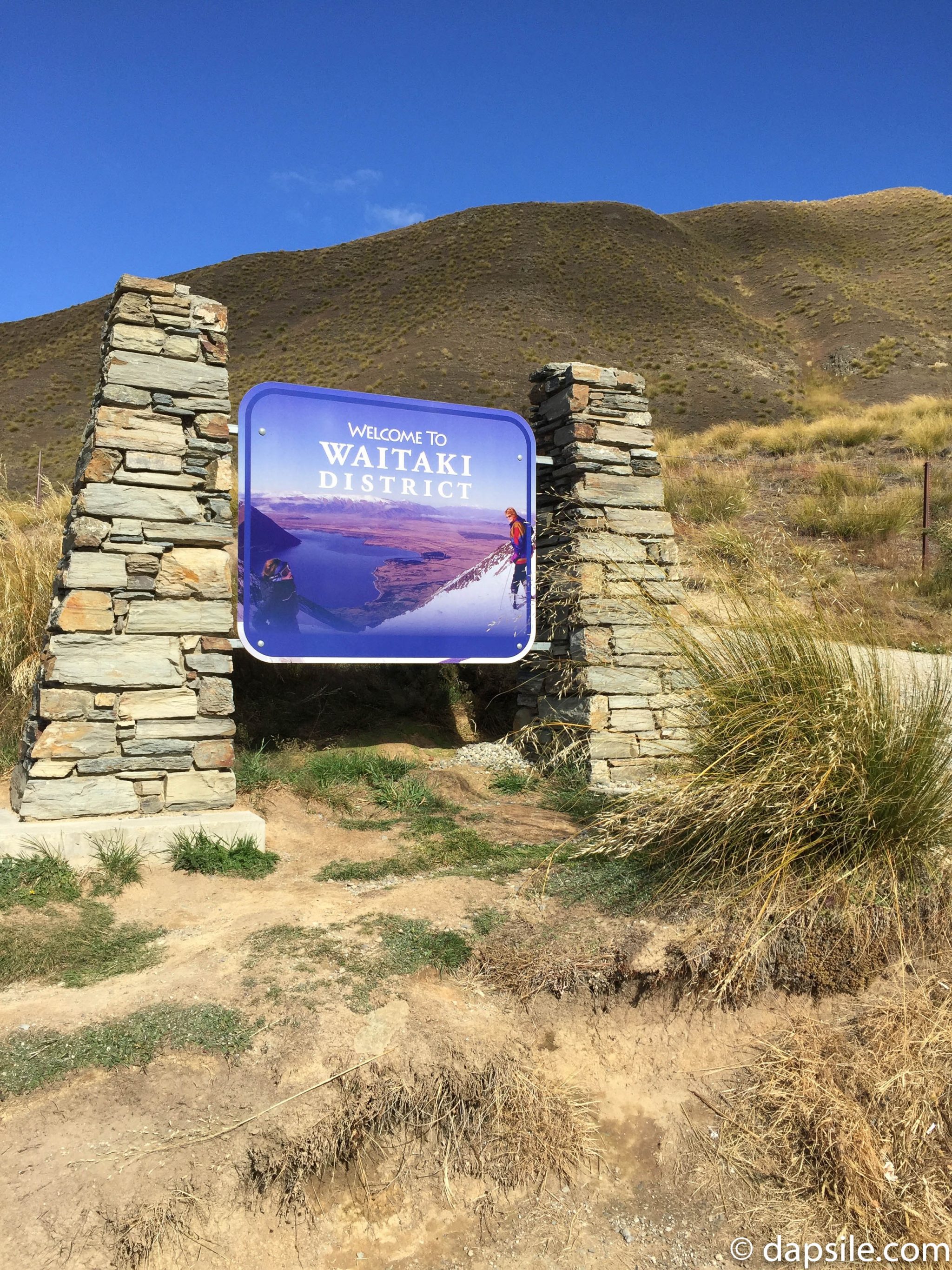 Welcome to Waitaki District sign in NZ on the side of the road with mountains in the background